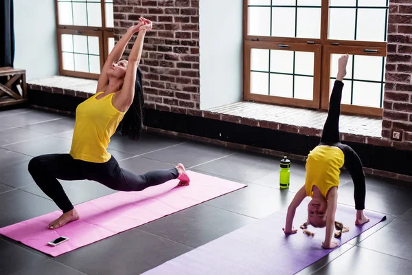 Mujer joven y niña haciendo ejercicios de estiramiento gimnástico en la estera en el gimnasio — Foto de Stock