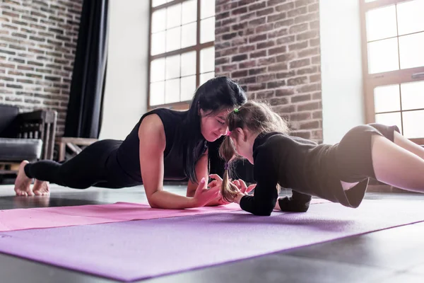Madre e hija trabajando juntas haciendo ejercicio de tablón en el club deportivo —  Fotos de Stock