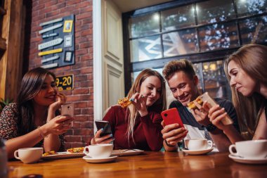 Onların hareket eden telefon içinde modern şık kafe bir yemek olan masa etrafında oturmuş kullanan gençlerin