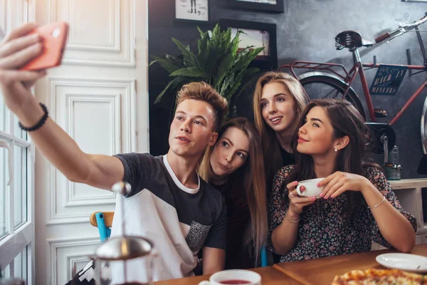 Grupo de adolescentes lindos tomando selfie con teléfono celular mientras están sentados en un restaurante con interior en estilo retro —  Fotos de Stock