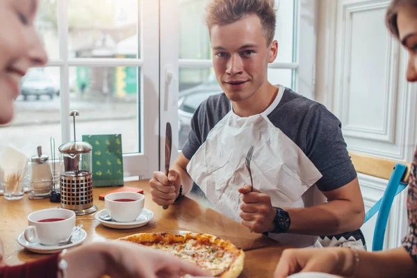 Stílusos tizenéves viselése szalvéta gazdaság kést és a villát készen áll a enni pizza ellen ablak étteremben ül — Stock Fotó