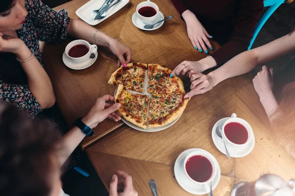 Top view of family members having lunch reaching out for pizza pieces in pizzeria — Stock Photo, Image