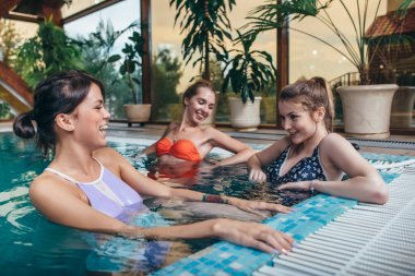 Kız arkadaşlar eğlenmeye spa merkezindeki kapalı yüzme havuzunda grup