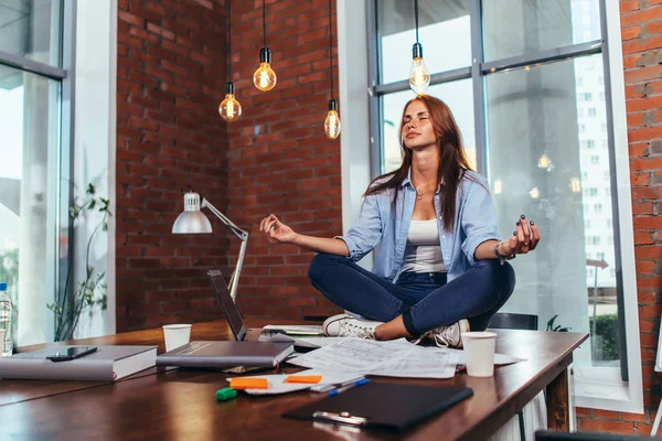 Estudante feminina sentada em lótus posar na mesa em seu quarto meditando relaxante depois de estudar e se preparar para o exame — Fotografia de Stock