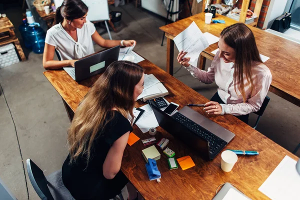 Kvinnliga studenter som arbetar på skola uppdrag använder bärbara datorer sitter vid skrivbord i ett grupprum — Stockfoto