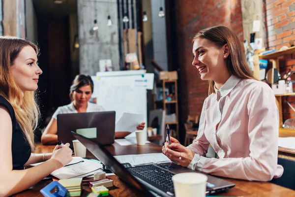 Team di donne d'affari che lavorano con documenti utilizzando computer portatili seduti alla scrivania in ufficio — Foto Stock