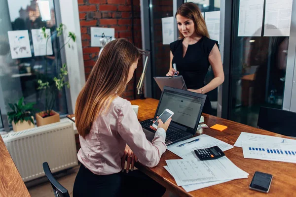 Mujer joven que usa ropa formal trabajando en computadoras portátiles escribiendo correos electrónicos sentados en su lugar de trabajo — Foto de Stock