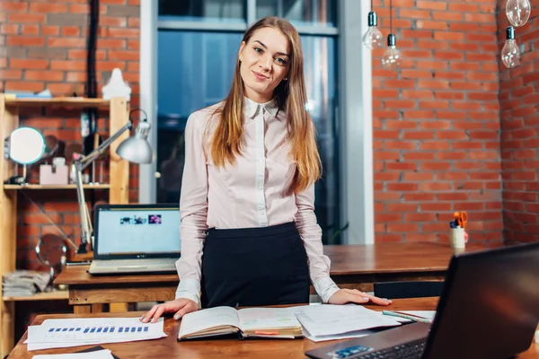 Directora de pie en su lugar de trabajo planeando su día de trabajo leyendo notas hechas en cuaderno —  Fotos de Stock