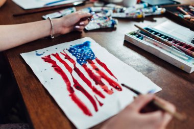 Genç kadın Illustrator işyerinde oturan aquarelle boya kullanarak ABD bayrağı çizim