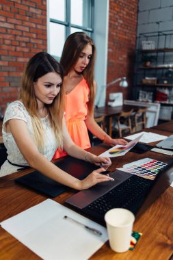 Genç ve güzel kadın grafik tasarımcı ofisinde masada oturan renk tablosu bakarak