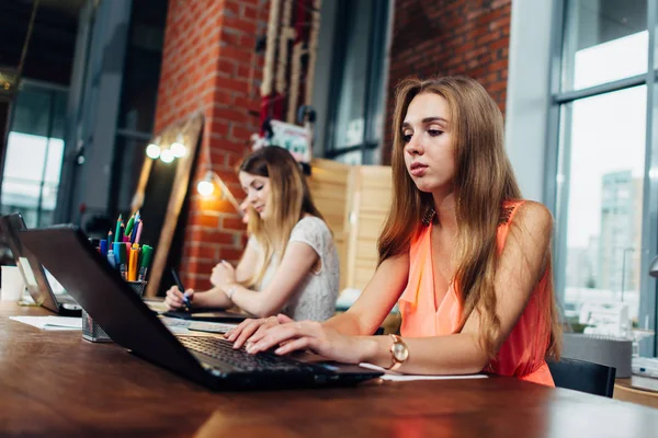 Команда женщин-дизайнеров интерьеров, использующих ноутбуки и цветные образцы во время рабочего процесса в стильном офисе — стоковое фото