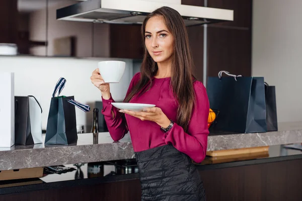 Chic jeune femme latine boire du café debout dans la cuisine détente après les achats — Photo