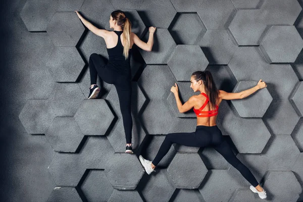 Fit women posing like a climber hanging on decorative wall — Stock Photo, Image