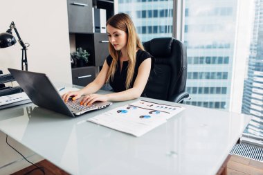 Ofiste masada oturan belgeleri ile çalışan kadın