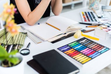 Yakın çekim Taslak çizim kalem kullanarak sketchbook bir kadın ressam görüş açısı. Sanatçı boya kalemi seti ile Sanat Atölyesi çizimi.