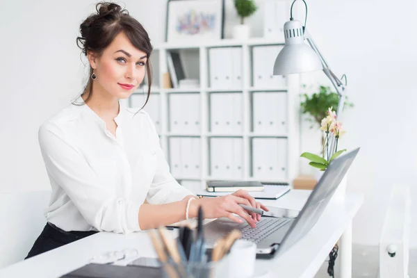 Jeune femme d'affaires assise sur son lieu de travail, élaborant de nouvelles idées d'affaires, portant un costume formel et des lunettes, regardant de côté . — Photo