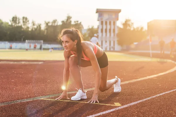 Mulher em posição inicial pronta para correr no estádio . — Fotografia de Stock