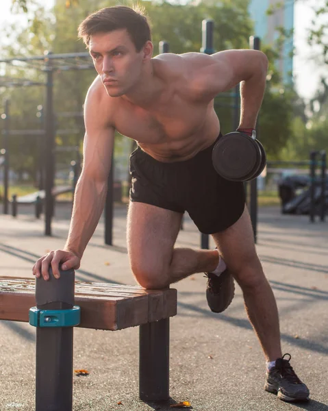 Atleta masculino muscular con los brazos levantados haciendo ejercicios de levantamiento de pesas. — Foto de Stock