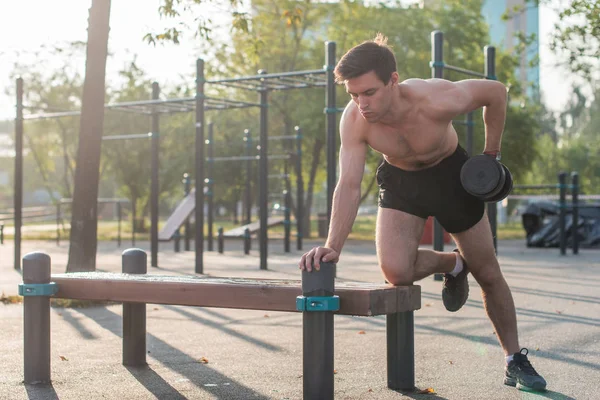 Atleta masculino muscular com braços levantados fazendo exercícios de elevação halteres . — Fotografia de Stock