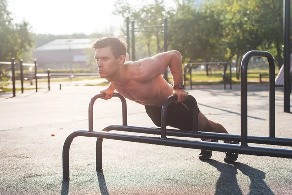 Jonge gespierde mannelijke atleet push-up beoefening in het park. — Stockfoto