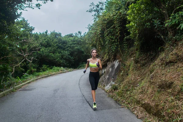 Kvinnlig idrott modell kör på väg i bergen. Fitness kvinna utbildning utomhus. — Stockfoto