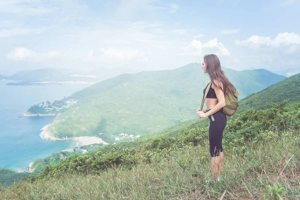 Plecak podróżny kobieta stoi na wzgórzu, patrząc na morze i góry. Trail runner przerwę ciesząc się widokiem natury — Zdjęcie stockowe