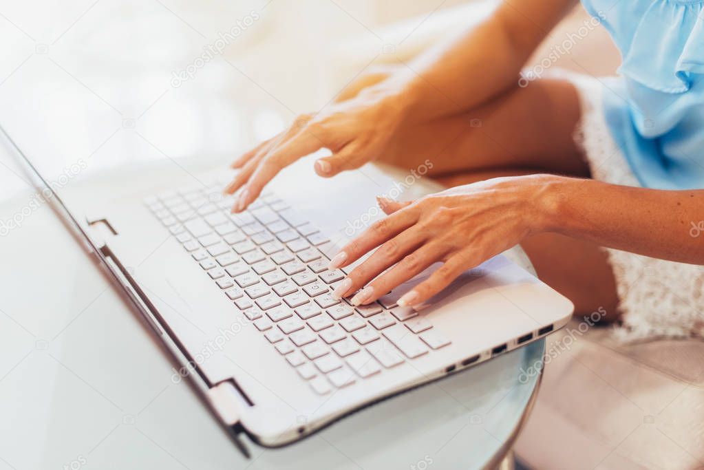 Close-up shot of female hands typing on laptop keyboard