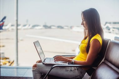 Havaalanı. Laptop klavye yazarak kullanan genç kadın