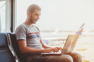 Havaalanı terminal dizüstü bilgisayar kullanan genç adam
