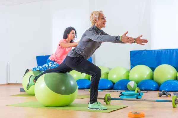 Sporty women doing stretching exercises with fitness stability ball in a sports club — Stock Photo, Image