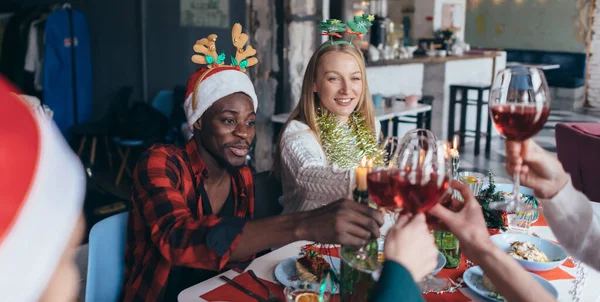 Gente celebrando Navidad o Año Nuevo clink vasos sentados a la mesa . —  Fotos de Stock