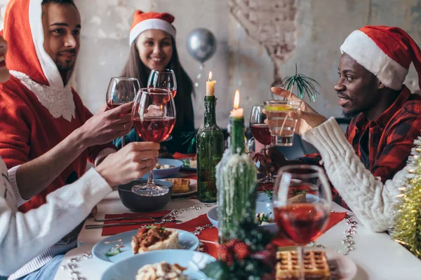 テーブルに座って、メガネをクリックして祝う人々。クリスマスまたは新年の前夜. — ストック写真