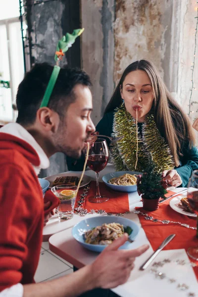 テーブルで陽気な友人はパスタを食べ、スパゲティは口からぶら下がり. — ストック写真