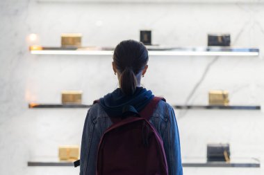 Genç kadın penceredeki kadın çantalarına bakıyor..