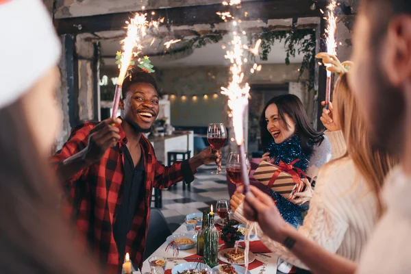 Freunde feiern. Lächelnde Menschen im Urlaub, die auf brennende Wunderkerzen anstoßen — Stockfoto