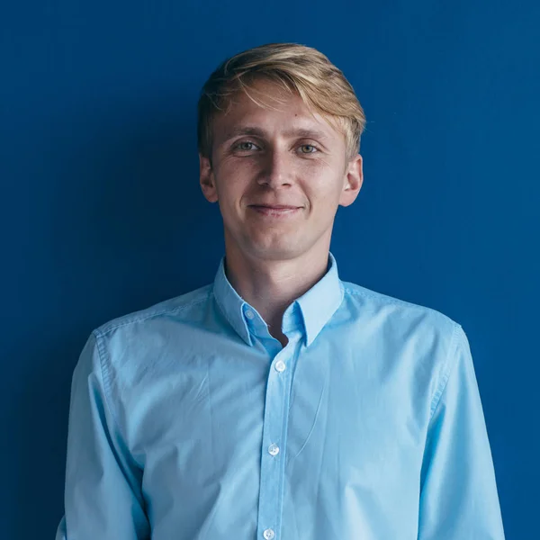Mavi arka planda duran genç bir adamın portresi — Stok fotoğraf
