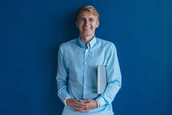 Portrait de jeune homme souriant et debout sur fond bleu — Photo