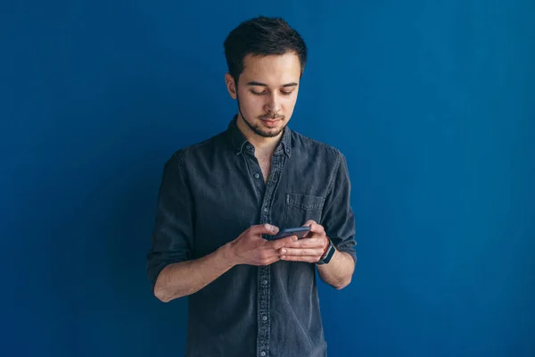 Junger Mann blickt auf sein Smartphone — Stockfoto