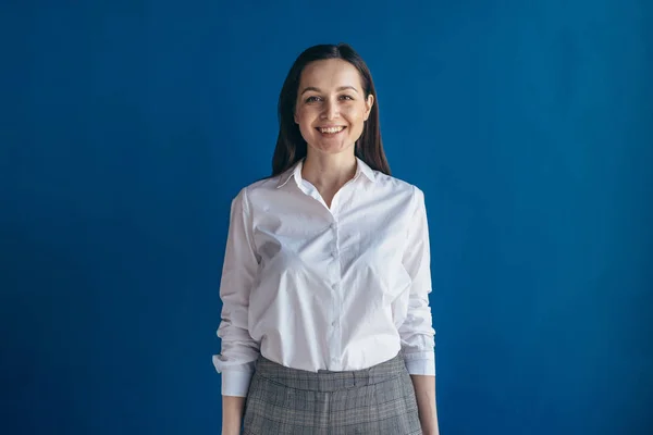 Porträtt av ung kvinna klädd i vit skjorta tittar på kameran med leende. Vit kvinna med brunt hår poserar inomhus — Stockfoto