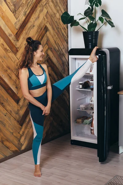 Woman open refrigerator door with her foot.