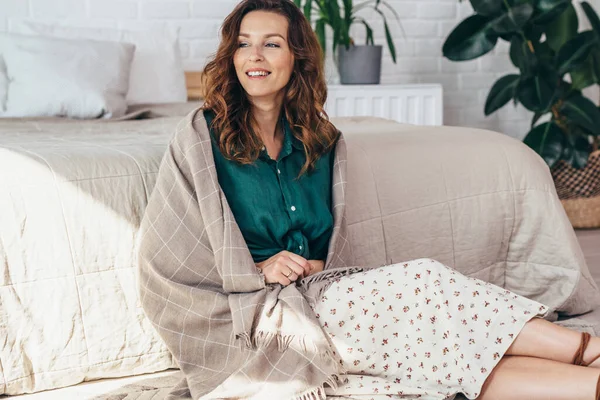 Chica sentada en el suelo junto a la cama en el dormitorio — Foto de Stock