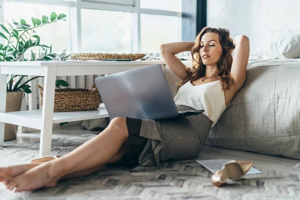 Mujer joven es relajante y el uso de ordenador portátil en casa — Foto de Stock