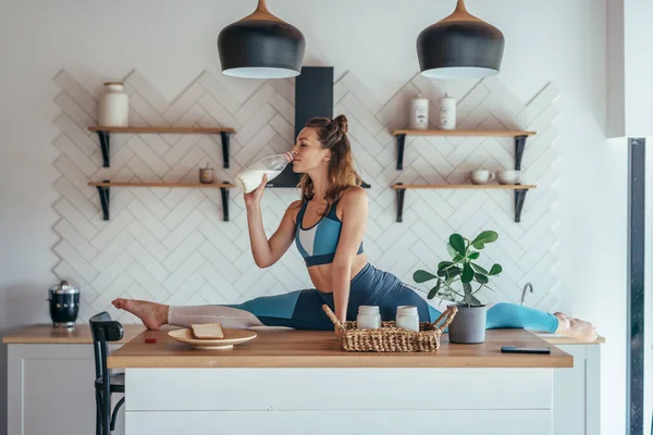 Fit femme en position divisée sur la table de cuisine prendre le petit déjeuner . — Photo