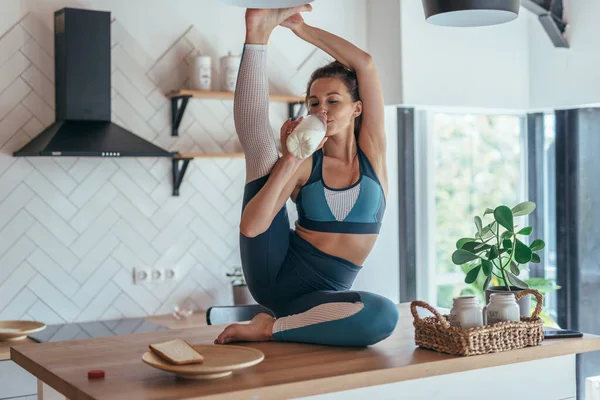 Ung kvinna dricker mjölk och gör en stretching motion. — Stockfoto