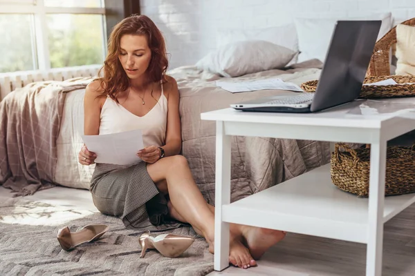 Joven mujer de negocios está sentada en el suelo de su dormitorio y leyendo. Quédate en casa. — Foto de Stock