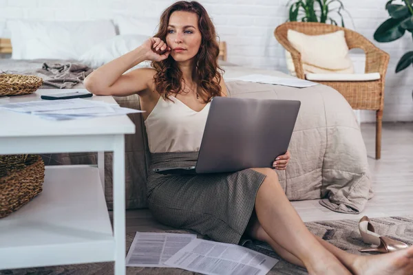 Portrait of young woman sitting on floor with laptop and looking away — Stock Photo, Image