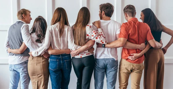 Group of young people hugging together Rear view — Stock Photo, Image