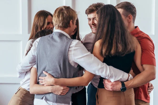 Circle of young people hugging each other.