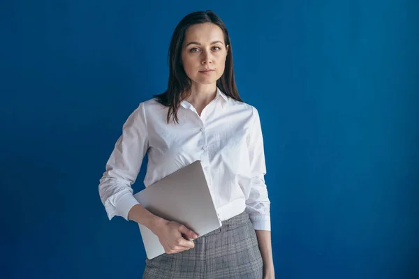 Portret van jonge serieuze zakenvrouw met laptop op zoek naar camera. — Stockfoto