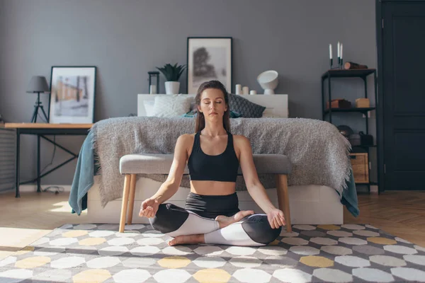Fit junge Frau trainiert zu Hause, macht Yoga-Übungen, entspannt und beruhigt. — Stockfoto